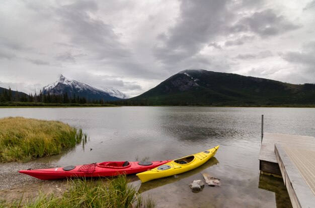 Kayaks rossi e gialli che si siedono da un bacino con una vista del monte Rundle sui laghi Vermillion