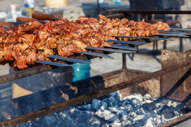 Kebab alla griglia che cucina su spiedino di metallo. Carne arrosto cotta al barbecue. Piatto orientale tradizionale, shish kebab. Griglia su carbonella e fiamma, picnic, street food