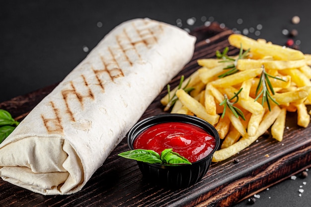 Kebab con pollo avvolto in pane pita con patatine fritte e salsa di pomodoro