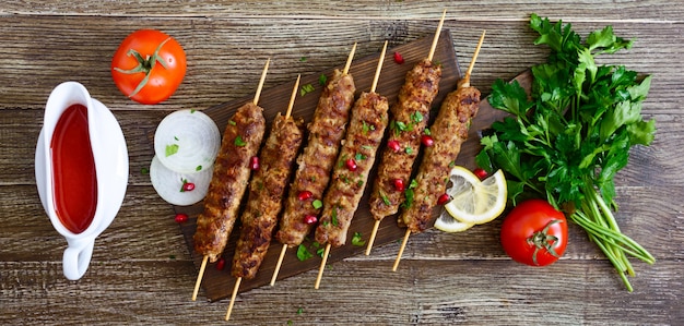 Kebab delizioso di lula su una tavola di legno. Carne tritata su spiedini di legno, grigliata. bandiera