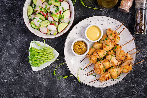 Kebab di pollo alla griglia e insalata con cetrioli, ravanelli e cipolla