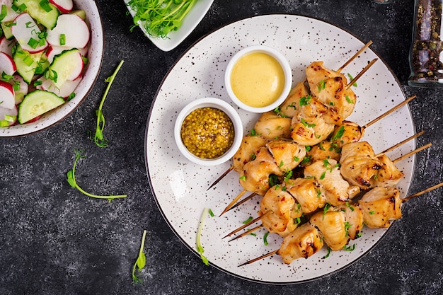 Kebab di pollo alla griglia e insalata con cetrioli, ravanelli e cipolla