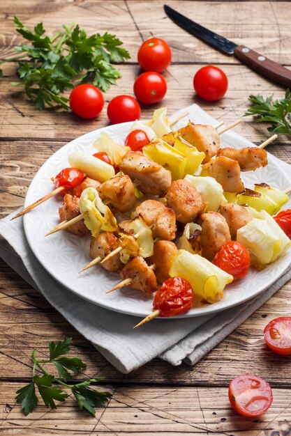 Kebab pollo, zucchine e pomodori su spiedini in un piatto.