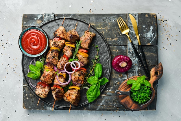 Kebab tradizionale. Succosi spiedini di maiale con verdure su una lastra di pietra nera. Barbecue. Vista dall'alto. Spazio libero per il testo.