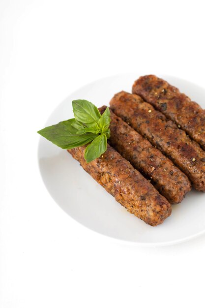 Kebab vegano di seitan con foglie di basilico su un piatto bianco.