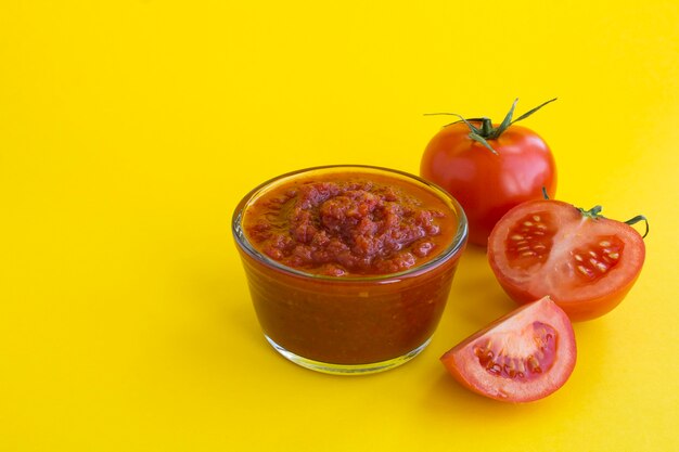 Ketchup fatto in casa nella ciotola di vetro sul tavolo giallo. Avvicinamento.