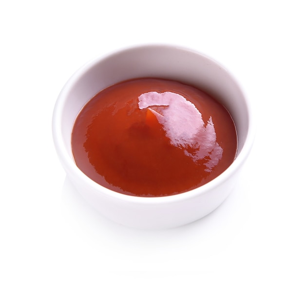 Ketchup in tazza di ceramica su sfondo bianco