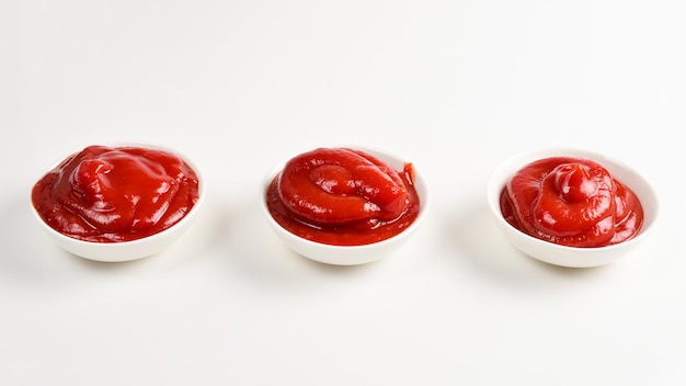 Ketchup nel piatto bianco su sfondo bianco.