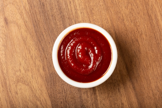 Ketchup nel ramekin su fondo di legno