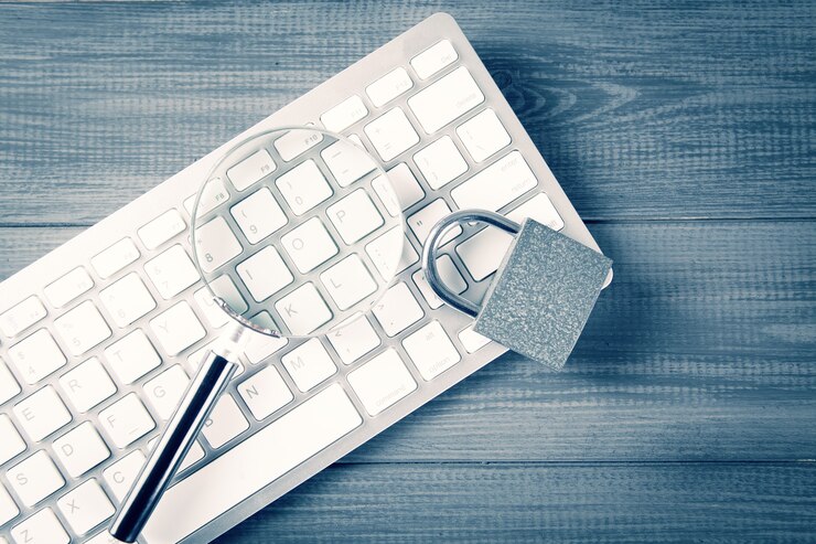 Photo keyboard, magnifier and lock. protection search concept. learned defenses. gray wooden table