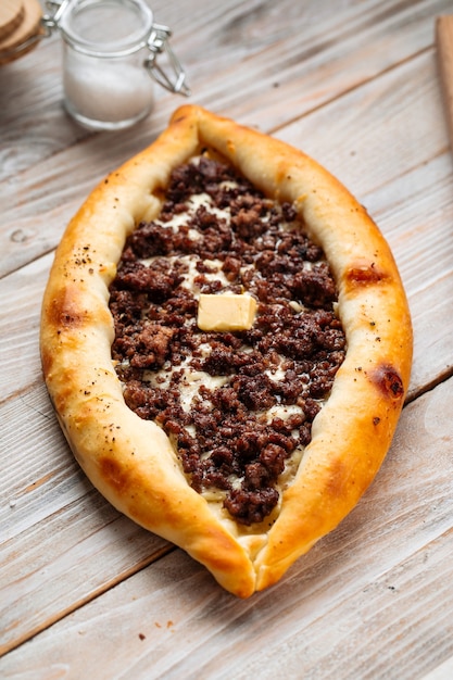 Khachapuri Adjarian ripieni di carne macinata sul tavolo di legno