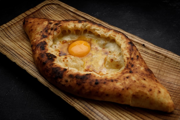 Khachapuri adjariano con un uovo su una tavola di legno