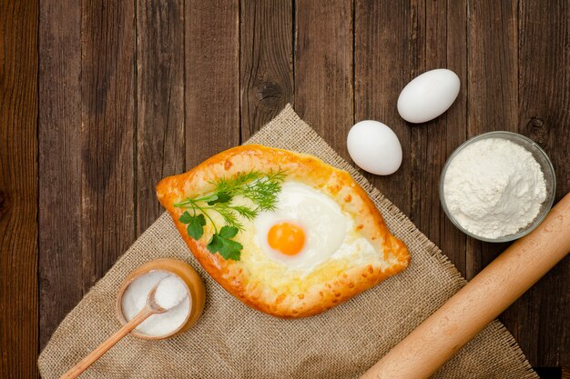 Khachapuri con uova vestirono, sale, farina e uova. Tavolo in legno, copia spazio