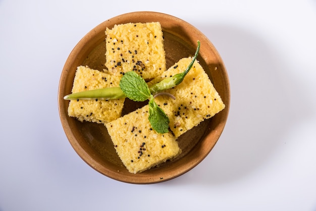 Khaman Dhokla è uno spuntino vegetariano o un prodotto per la colazione proveniente dallo stato indiano del Gujarat. servito con peperoncino verde fritto