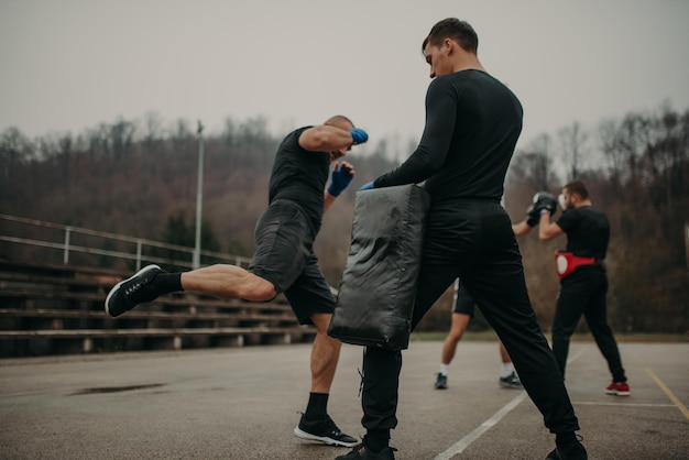 Kick box di allenamento dell'uomo con il suo allenatore professionista