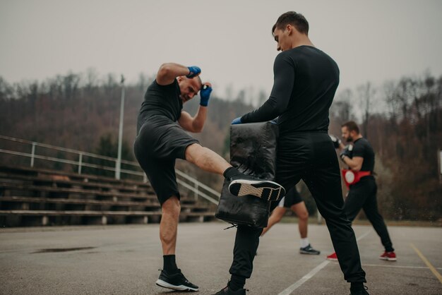 Kick box di allenamento dell'uomo con il suo allenatore professionista