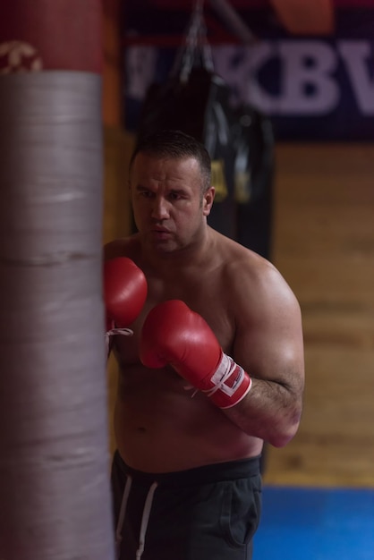 kick boxer muscolare professionale si allena su un sacco da boxe mentre si prepara per il prossimo combattimento