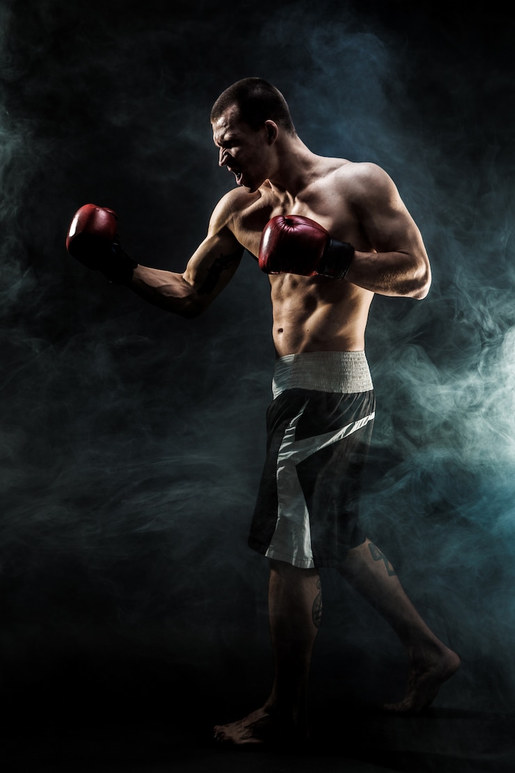 Foto kickbox muscolare o combattente tailandese muay che perfora nel fumo