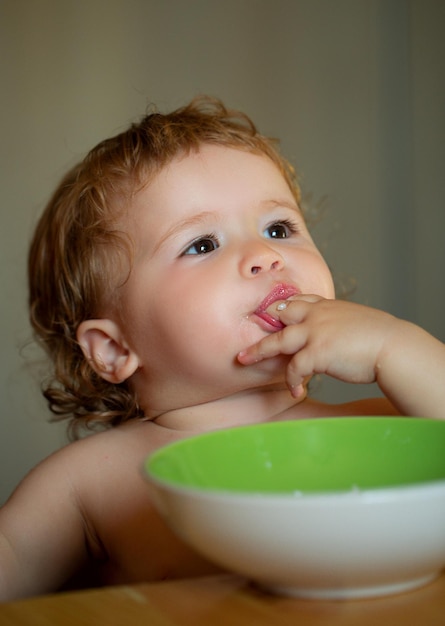 Kid baby mangia la zuppa in cucina con piatti e cucchiaio