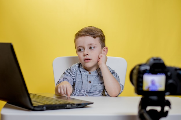 Kid blogger riprese video sulla fotocamera che lavora con il computer portatile.