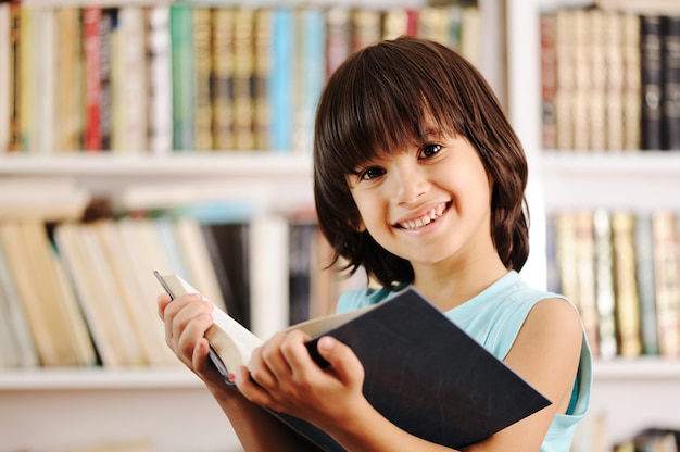 Kid con il libro in biblioteca