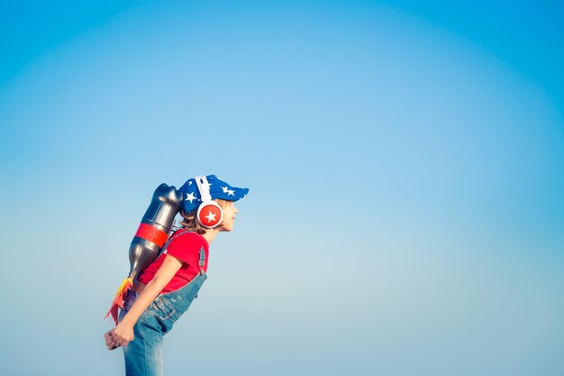 Kid con jet pack contro il cielo blu. Bambino che gioca all'aperto. Concetto di successo, leader e vincitore