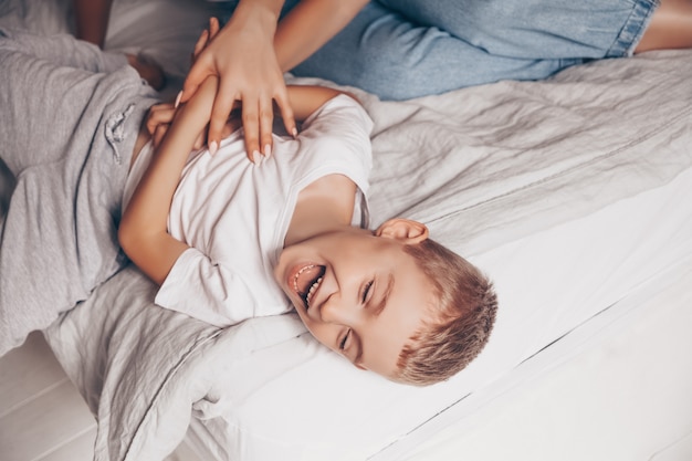 Kid divertirsi e ridere sul letto bianco