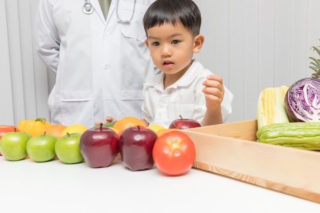 Kid imparare la nutrizione con il medico per scegliere come mangiare frutta e verdura fresca.