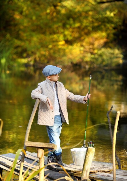 Kid pesca in un fiume seduto su un pontone di legno