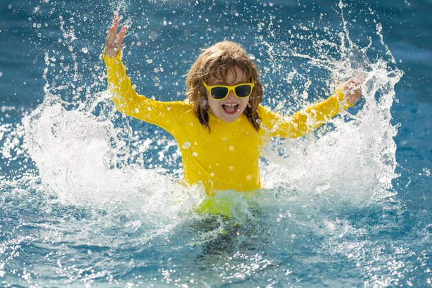 Kid spruzzi in piscina d'acqua estiva kid splash in piscina eccitato ragazzino felice che salta in piscina