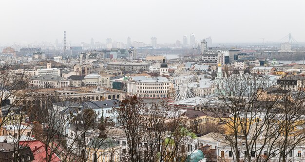 Kiev, Ucraina - 16 novembre 2019: Paesaggio urbano del distretto di Podol nella città di Kiev al giorno nebbioso. Piazza Kontraktova e ruota panoramica