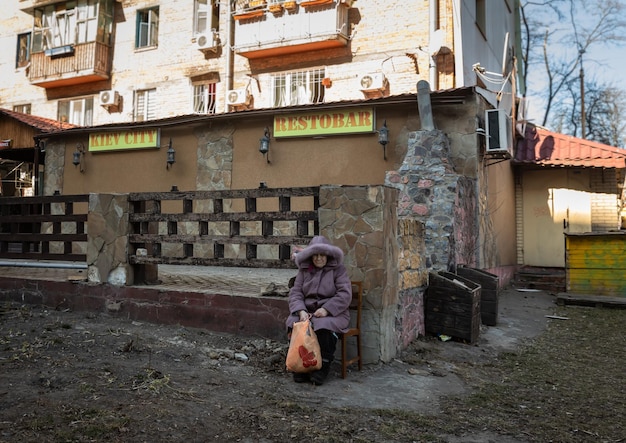 KIEV UCRAINA 18 marzo 2022 Guerra in Ucraina Una donna anziana di una casa distrutta si siede fuori vicino alla sua casa Edifici residenziali danneggiati a seguito di un bombardamento nel distretto di Podilskyi