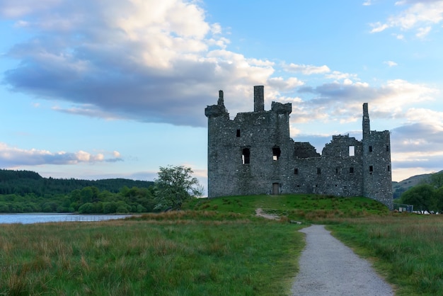 Kilchurn Castle , nella cura di Historic Environment Scotland , è una struttura in rovina su una penisola rocciosa a Loch Awe al crepuscolo , Argyll and Bute, Scozia