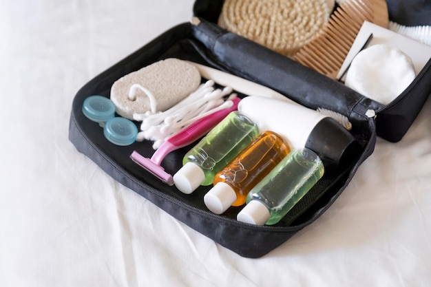 Kit di cosmetici da viaggio con bottiglie, spazzole e cosmetici sul letto