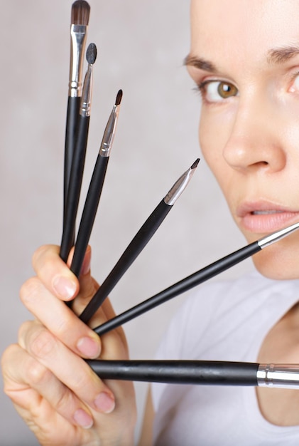 Kit pennelli trucco vicino al viso di una giovane donna tra i 30 e i 35 anni. Avvicinamento