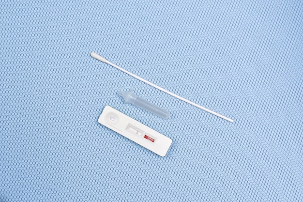 Kit per il test dell'antigene ATK Covid19 risultato negativo del test su sfondo di colore azzurro con un tampone in tubetto di cotone per l'estrazione della cassetta