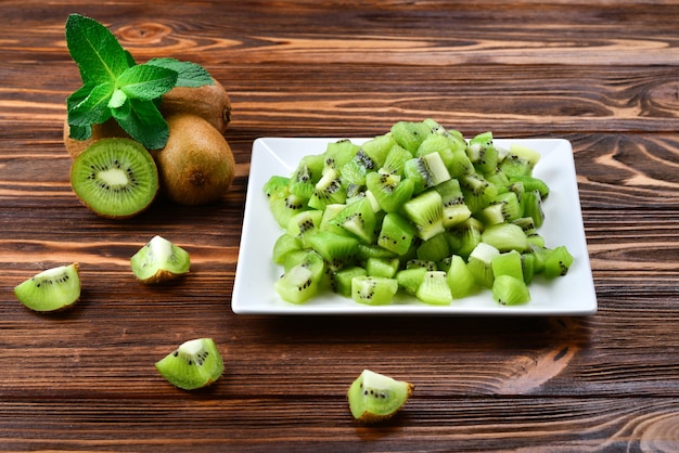 Kiwi appena affettato con kiwi interi in background.