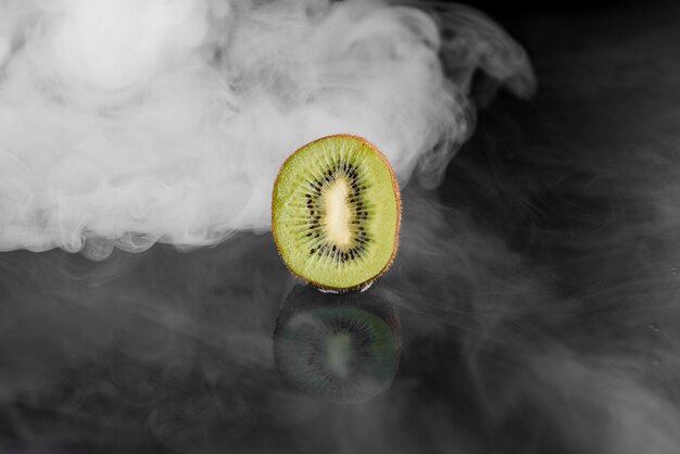 Kiwi con fumo sulla superficie nera