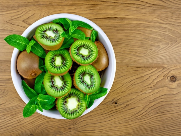 Kiwi e foglie di menta nella ciotola su un tavolo di legno