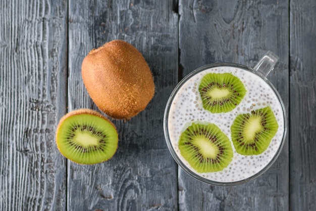 Kiwi e una tazza di budino di semi di Chia nero su un tavolo di legno nero. La vista dall'alto. Disteso.