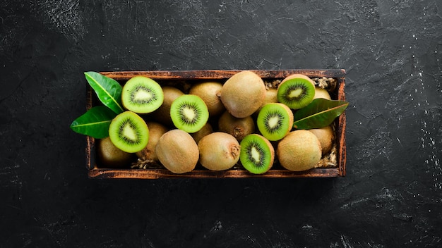 Kiwi fresco e foglie verdi in una scatola di legno sullo sfondo vecchio Frutta Vista dall'alto Spazio libero per il testo