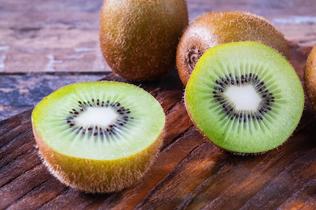 Kiwi fresco tagliato a metà su un tagliere di legno.