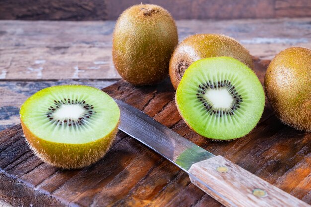 Kiwi fresco tagliato a metà su un tagliere di legno.