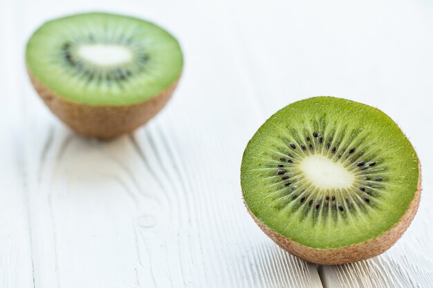 Kiwi fresco tagliato a metà su un tavolo di legno bianco Vista frontale