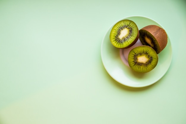 Kiwi isolato sul piatto, fondo verde. Taglio di kiwi dolce verde. Disintossicazione, perdita di peso, alimentazione vegetariana. dieta sana .