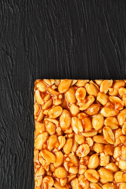 Kozinaki di boletus dorato da barrette energetiche di fagioli di arachidi tostate. Sfondo nero strutturale, vista dall'alto
