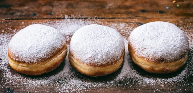 Krapfen con zucchero a velo tre e isolato su sfondo di legno