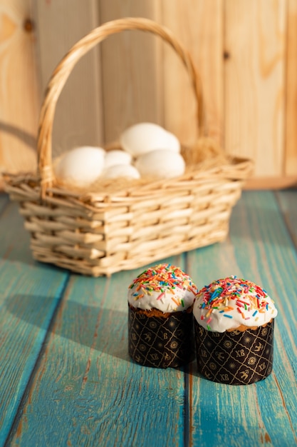 Kulich pasquale e uova in un cesto sul fieno. tavolo in legno turchese.