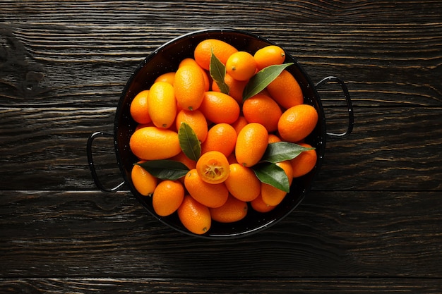 Kumquat in ciotola su sfondo di legno scuro vista dall'alto