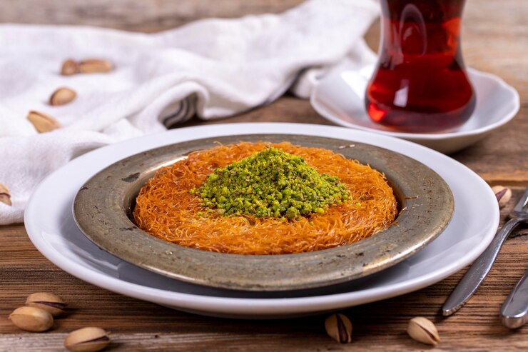 Kunefe Cucina tradizionale turca Kunefe con pistacchi su sfondo di legno da vicino